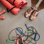 Fitness equipment including shoes, mats, weights, and skipping ropes on a gym floor.